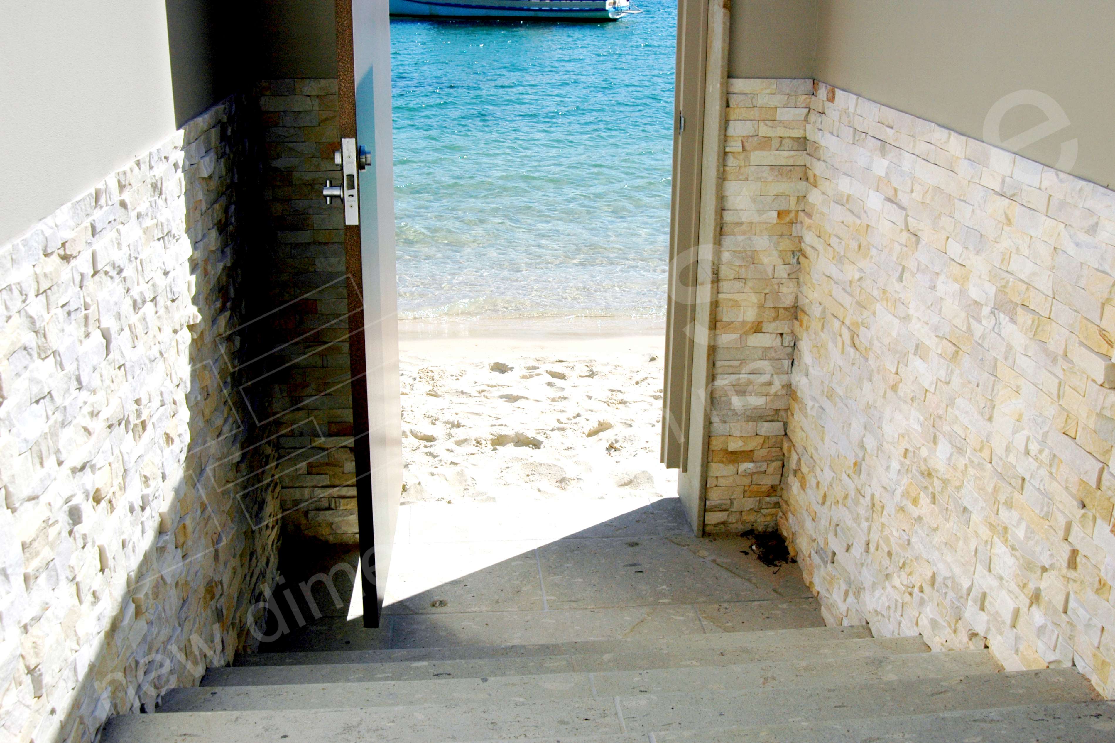 Steps leading from the backyard of a private residence in Australia to a small beach with stacked stone on the walls